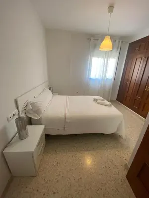 a bedroom with a white bed and a night stand at Apartamento en Jerez de la Frontera in Jerez de la Frontera