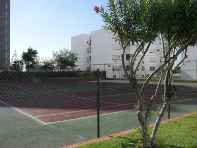 a tennis court with a tree in the foreground at Piso Con Hermosas Vistas Al Mar in El Puerto de Santa María