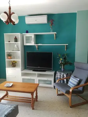 a living room with a tv and a chair at Piso Con Hermosas Vistas Al Mar in El Puerto de Santa María