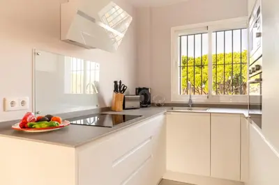 a white kitchen with a bowl of fruit on the counter at Penthouse Sol y Mar in Poblado de Sancti Petri