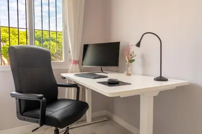 a white desk with a computer and a chair at Penthouse Sol y Mar in Poblado de Sancti Petri