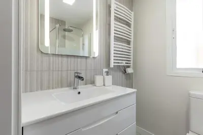 a white bathroom with a sink and a mirror at Penthouse Sol y Mar in Poblado de Sancti Petri