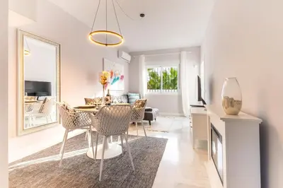 a dining room and living room with a table and chairs at Penthouse Sol y Mar in Poblado de Sancti Petri