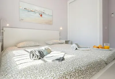 a white bedroom with a bed with towels on it at Penthouse Sol y Mar in Poblado de Sancti Petri