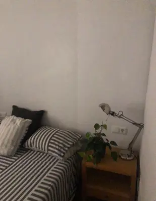 a bedroom with a bed and a lamp on a night stand at Apartamento San Bartolomé in El Puerto de Santa María