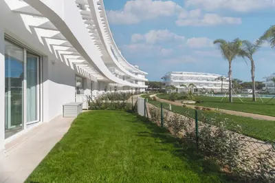 an external view of a white building with grass at Oasis playa costa Ballena in Costa Ballena