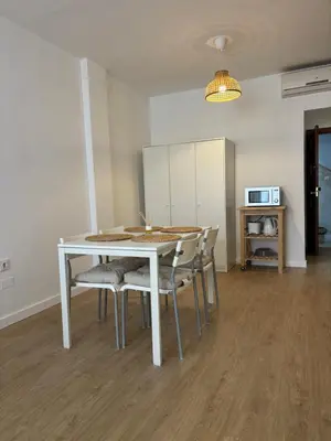 a dining room with a white table and chairs at Apartamentos Banda Playa in Sanlúcar de Barrameda