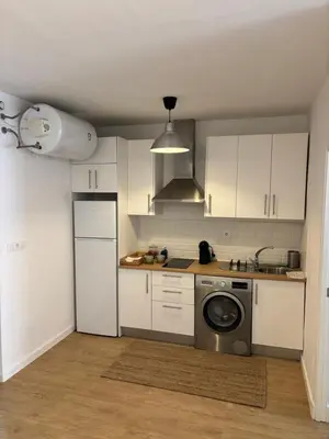 a kitchen with white cabinets and a washing machine at Apartamentos Banda Playa in Sanlúcar de Barrameda