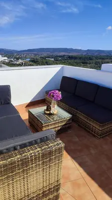 a patio with a couch and a table with flowers at El mirador de Beatriz in Arcos de la Frontera