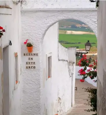 an archway in a white building with a sign at Casa Encarnita in Arcos de la Frontera