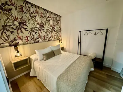 a bedroom with a white bed with a floral wallpaper at Solera Suites in Jerez de la Frontera