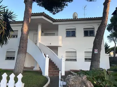 a white house with a white staircase and trees at Apartamento La Barrosa Beach in Novo Sancti Petri