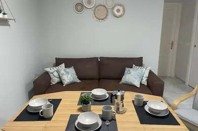 a living room with a table and a brown couch at Apartamento La Barrosa Beach in Novo Sancti Petri