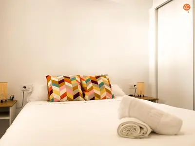 a bedroom with a white bed and two tables at La Palmera Grupo AC Gestion in Cádiz