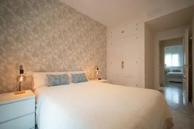 a bedroom with a large white bed with blue pillows at Apartamento Centro&Playa Sanlucar - V Centenario in Sanlúcar de Barrameda
