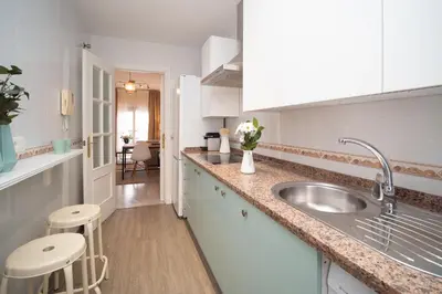a kitchen with a sink and two stools at Apartamento Centro&Playa Sanlucar - V Centenario in Sanlúcar de Barrameda