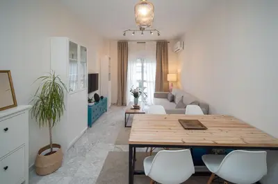 a living room with a wooden table and white chairs at Apartamento Centro&Playa Sanlucar - V Centenario in Sanlúcar de Barrameda