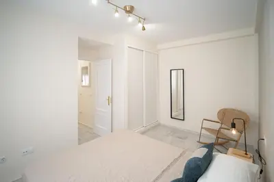 a white bedroom with a bed and a mirror at Apartamento Centro Sanlucar - Banda Playa in Sanlúcar de Barrameda