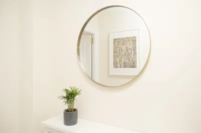 a mirror on a white wall in a bathroom with a plant at Apartamento Centro Sanlucar - Banda Playa in Sanlúcar de Barrameda