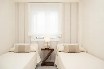 two beds in a white room with a window at Apartamento Centro Sanlucar - Banda Playa in Sanlúcar de Barrameda