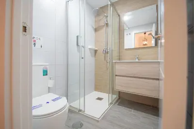 a bathroom with a toilet and a glass shower at Soto Urban Apartment in Cádiz