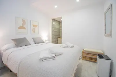 a white bedroom with a large bed with towels on it at Soto Urban Apartment in Cádiz