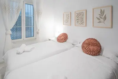 two white beds in a room with a window at Soto Urban Apartment in Cádiz