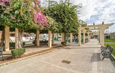a park with benches and trees with pink flowers at Nice Apartment In Chipiona With Wifi in Chipiona