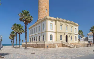 a large brick building with a chimney and palm trees at Nice Apartment In Chipiona With Wifi in Chipiona