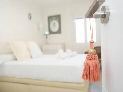 a bedroom with a white bed with a tassel on the door at SibsSanlucar Calma - Centro y Playa - Nuevo in Sanlúcar de Barrameda