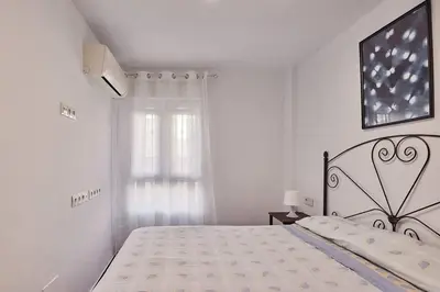 a white bedroom with a large bed and a window at Gades Zuloaga Ha in Cádiz