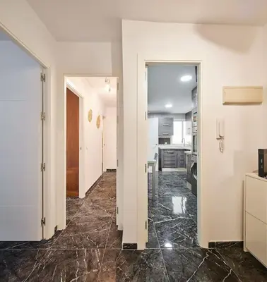 a hallway with white walls and marble floors in a room at Gades Zuloaga Ha in Cádiz