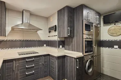 a kitchen with wooden cabinets and a washer and dryer at Gades Zuloaga Ha in Cádiz