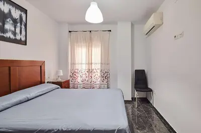a bedroom with a bed and a chair and a window at Gades Zuloaga Ha in Cádiz