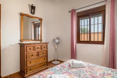 a bedroom with a bed and a dresser with a mirror at Villa Marta Clara in Conil de la Frontera
