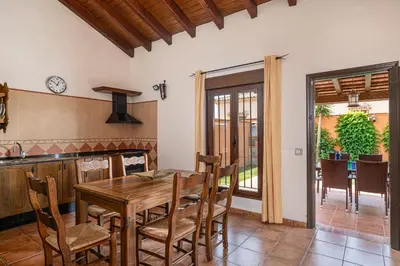 a kitchen and dining room with a wooden table and chairs at Villa Marta Clara in Conil de la Frontera