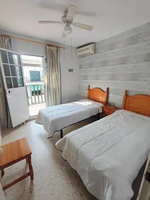 a bedroom with two beds and a window and a ceiling fan at Apartamento en Chiclana de la Frontera in Chiclana de la Frontera