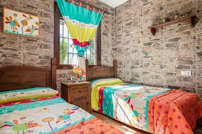a bedroom with two beds and a stone wall at Casa Cala Puntalejo in Conil de la Frontera