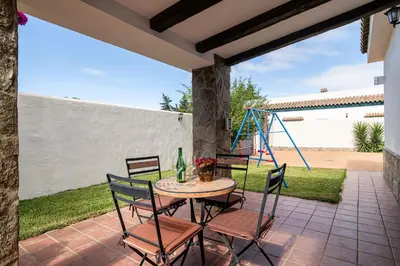 a patio with a table and chairs and a playground at Casa Cala Puntalejo in Conil de la Frontera