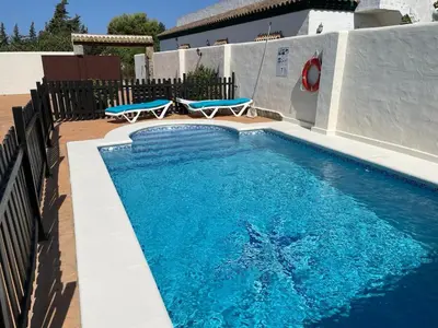 a swimming pool with two blue chairs next to it at Casa Cala Puntalejo in Conil de la Frontera