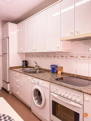 a kitchen with white cabinets and a washing machine at El Pelícano Parking free Grupo Ac Gestion in Cádiz
