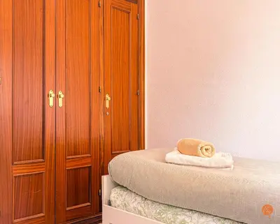 a bedroom with a bed and a wooden cabinet at El Pelícano Parking free Grupo Ac Gestion in Cádiz