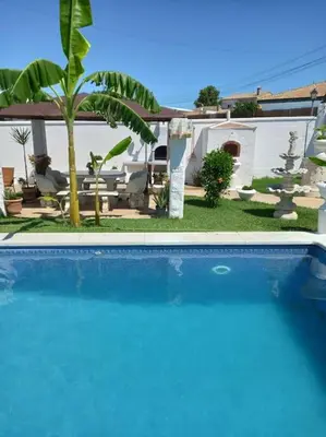 a swimming pool in front of a house with a palm tree at Villa completa con piscina en Arcos de la frontera in Arcos de la Frontera