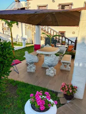 a patio with a table and chairs and flowers at Villa completa con piscina en Arcos de la frontera in Arcos de la Frontera