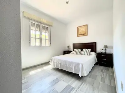 a white bedroom with a bed and a window at La Serena, Unifamiliar adosada en La Barrosa in Chiclana de la Frontera