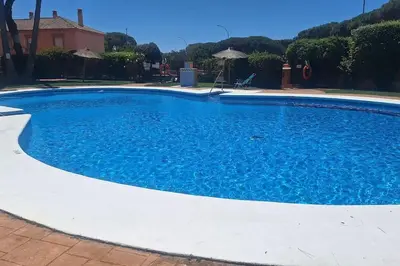 a large blue swimming pool in a yard at La Serena, Unifamiliar adosada en La Barrosa in Chiclana de la Frontera