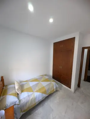 a bedroom with a bed and a wooden cabinet at Casa Brake in Chiclana de la Frontera