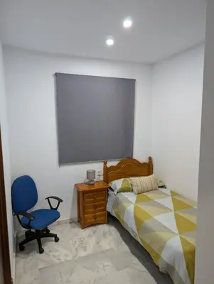 a bedroom with a bed and a blue chair at Casa Brake in Chiclana de la Frontera