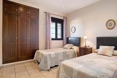 a bedroom with two beds and a cabinet and a window at Casa Borpa - Solo Familias in Conil de la Frontera
