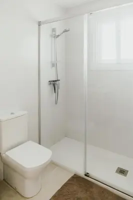 a white bathroom with a toilet and a shower at Casa Bahía in El Puerto de Santa María
